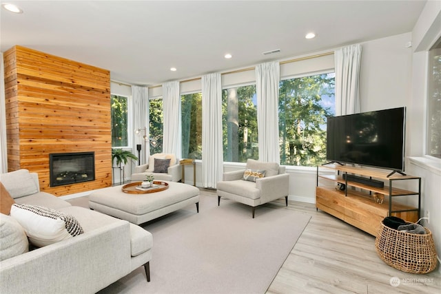 living room featuring a tile fireplace, a wealth of natural light, and light hardwood / wood-style flooring