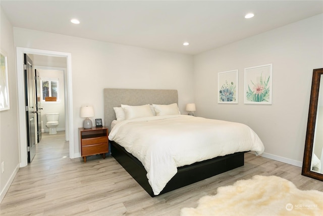 bedroom featuring connected bathroom and light hardwood / wood-style flooring