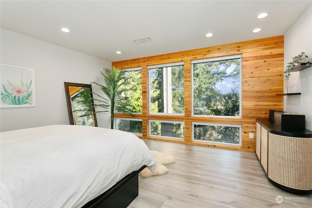 bedroom with light hardwood / wood-style flooring and wood walls