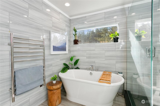 bathroom featuring tile walls, radiator heating unit, and independent shower and bath