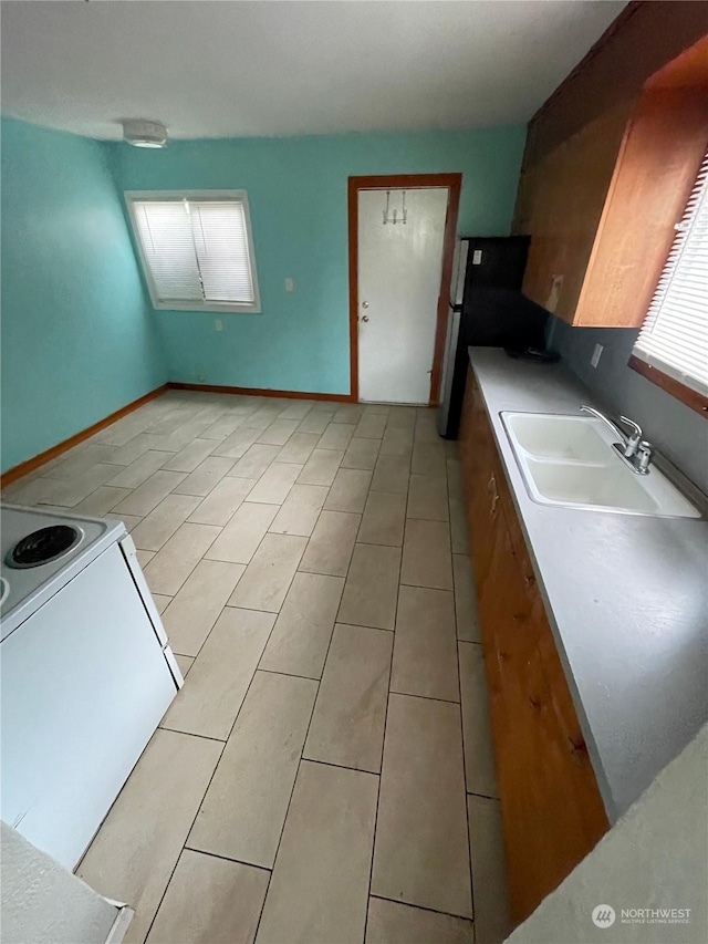 kitchen with white electric range, stainless steel fridge, sink, and light tile patterned floors