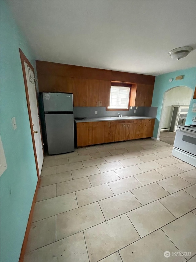 kitchen featuring sink, stainless steel fridge, white electric range oven, and light tile patterned floors