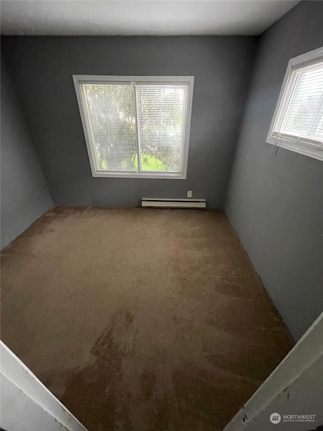 empty room featuring baseboard heating and carpet floors