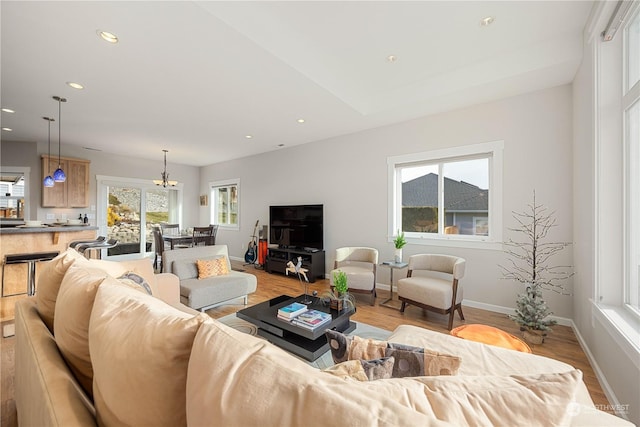 living room with light wood-type flooring, recessed lighting, a chandelier, and baseboards