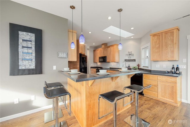 kitchen featuring a peninsula, black appliances, dark countertops, and decorative light fixtures