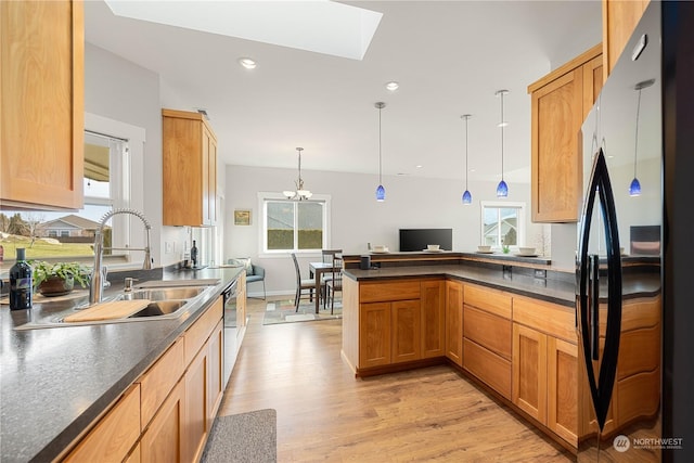 kitchen featuring freestanding refrigerator, pendant lighting, a sink, and dark countertops