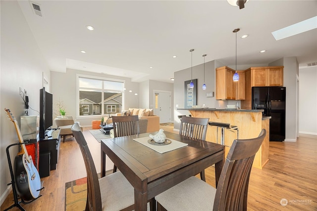 dining area with a skylight and light hardwood / wood-style flooring