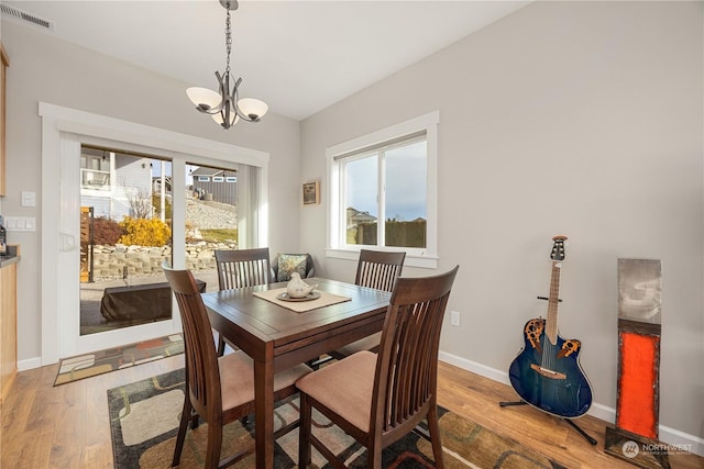 dining space with an inviting chandelier, baseboards, visible vents, and wood finished floors