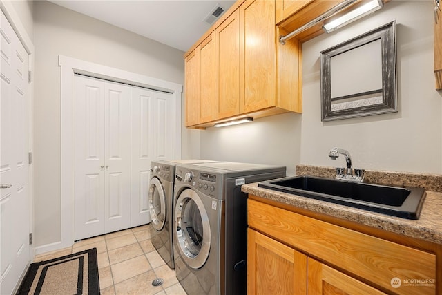 washroom featuring light tile patterned floors, a sink, visible vents, cabinet space, and washing machine and clothes dryer