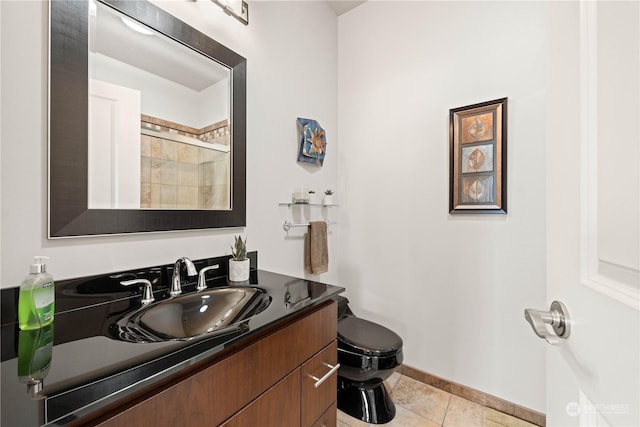 bathroom featuring tile patterned flooring, vanity, toilet, and walk in shower