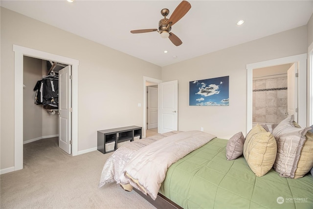 carpeted bedroom featuring a closet, a walk in closet, ceiling fan, and ensuite bath