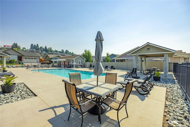 community pool with a patio, fence, and a residential view