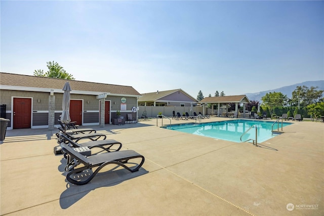 pool with a patio area, fence, and a mountain view