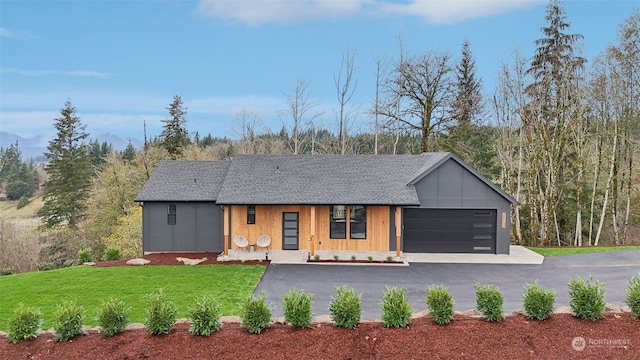 view of front of house with a garage, covered porch, and a front lawn