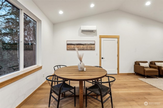 dining area with vaulted ceiling, an AC wall unit, a healthy amount of sunlight, and light wood-type flooring