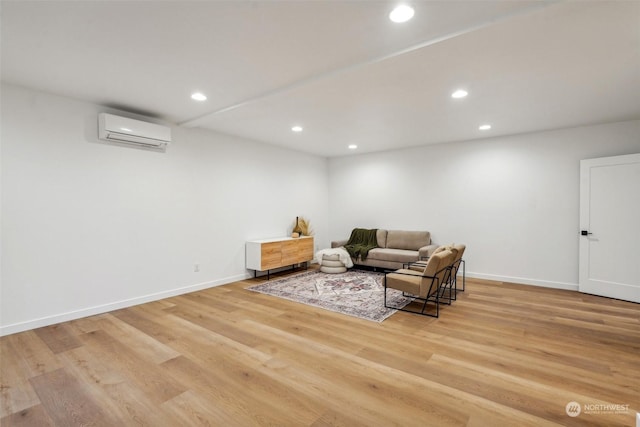 sitting room featuring an AC wall unit and light wood-type flooring