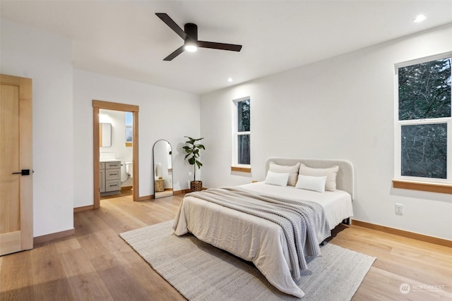 bedroom featuring ceiling fan, ensuite bath, and light hardwood / wood-style flooring