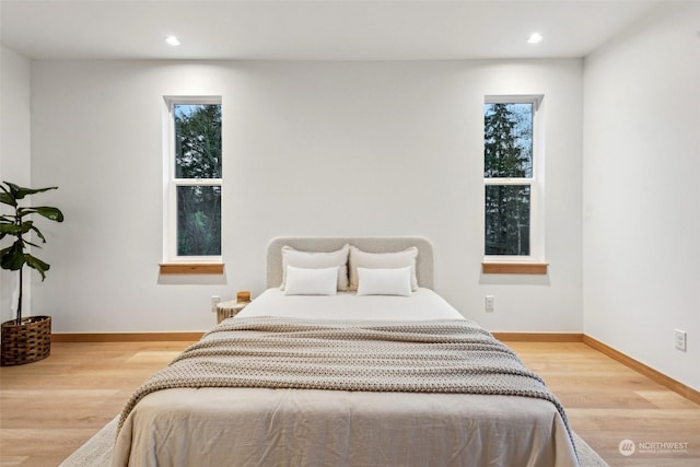 bedroom with light hardwood / wood-style floors and multiple windows