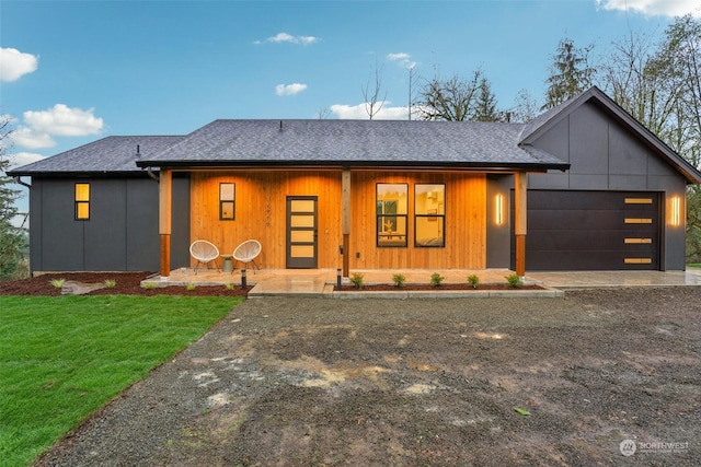 view of front of home with a garage, a porch, and a front lawn