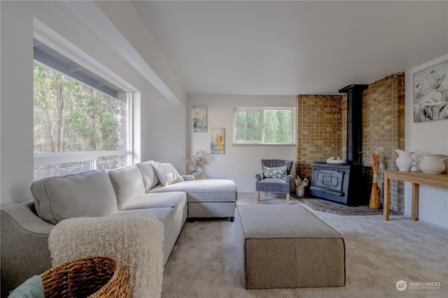 carpeted living room with brick wall, a healthy amount of sunlight, and a wood stove