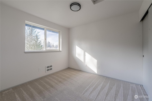 unfurnished room featuring heating unit and light carpet