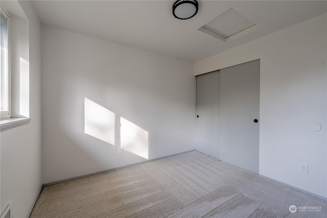 unfurnished bedroom featuring light colored carpet and a closet