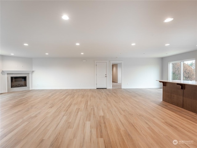 unfurnished living room with a tile fireplace and light hardwood / wood-style floors