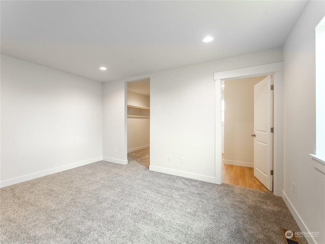 unfurnished bedroom featuring a closet, a spacious closet, and light carpet