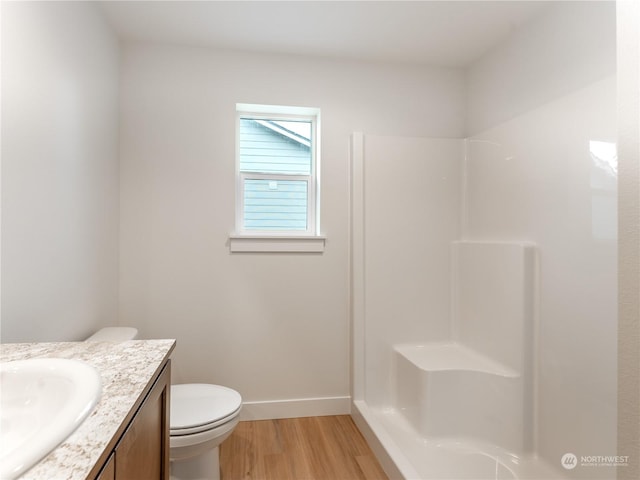 bathroom featuring wood-type flooring, toilet, vanity, and a shower