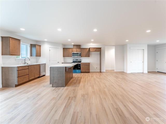 kitchen featuring sink, a breakfast bar, appliances with stainless steel finishes, a center island, and light hardwood / wood-style floors