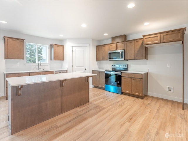 kitchen featuring sink, a breakfast bar area, a center island, light wood-type flooring, and range with electric stovetop