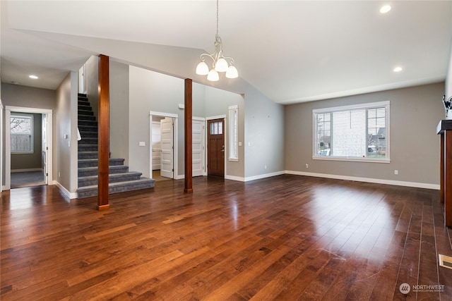 unfurnished living room with dark wood-type flooring, an inviting chandelier, and vaulted ceiling