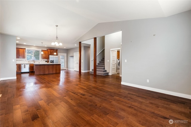 unfurnished living room featuring dark wood-type flooring, lofted ceiling, washer / dryer, and sink