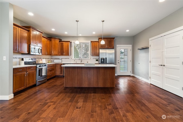 kitchen with sink, a center island, hanging light fixtures, dark hardwood / wood-style floors, and stainless steel appliances