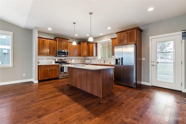 kitchen featuring lofted ceiling, hanging light fixtures, stainless steel appliances, a kitchen island, and decorative backsplash