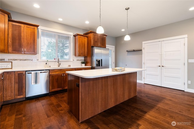 kitchen featuring sink, dark wood-type flooring, hanging light fixtures, stainless steel appliances, and a center island