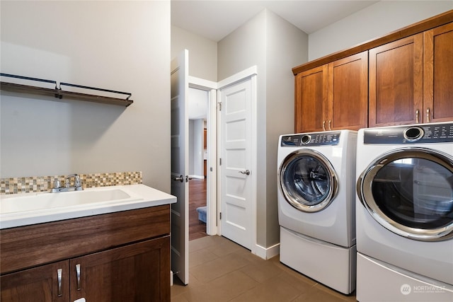 laundry room with cabinets, washer and dryer, sink, and dark tile patterned floors