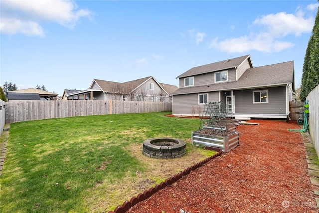 back of house with a yard and an outdoor fire pit