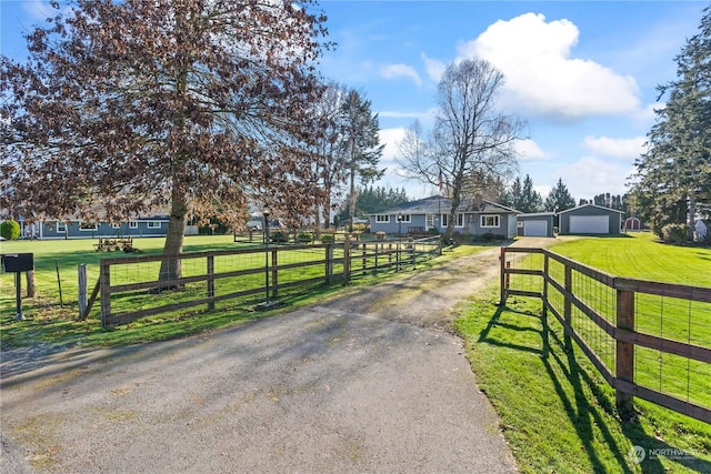 exterior space with a rural view, a front lawn, fence, and driveway