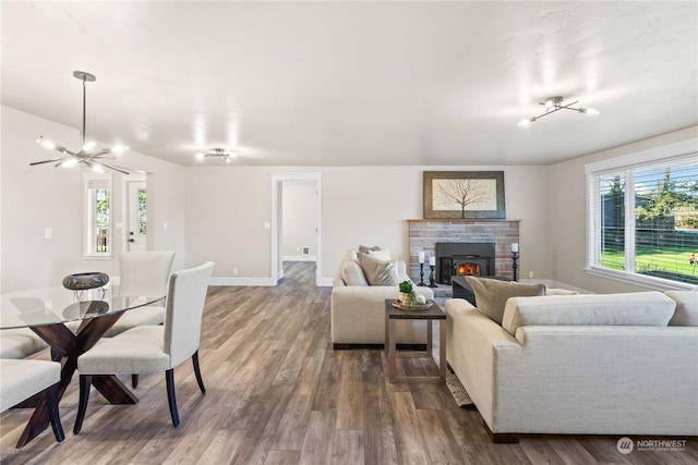 living room with dark hardwood / wood-style floors, a chandelier, and a stone fireplace