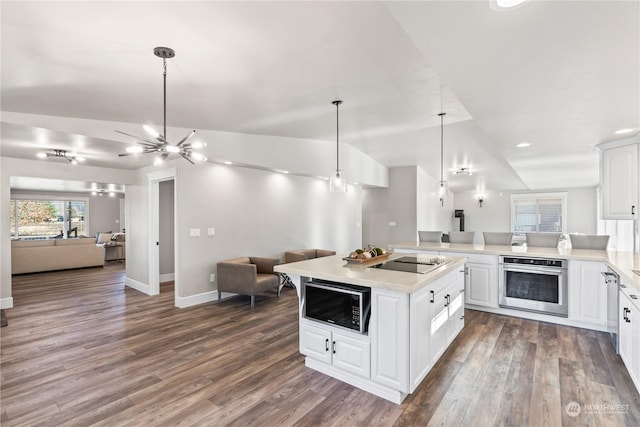 kitchen with pendant lighting, vaulted ceiling, black appliances, and white cabinets