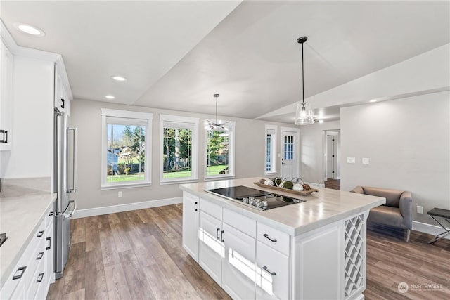 kitchen featuring lofted ceiling, hanging light fixtures, white cabinets, a kitchen island, and black electric cooktop