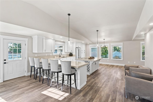 kitchen featuring pendant lighting, sink, white cabinets, hardwood / wood-style flooring, and a center island