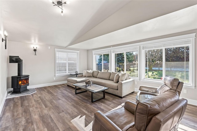 living room featuring vaulted ceiling, a wood stove, and hardwood / wood-style floors