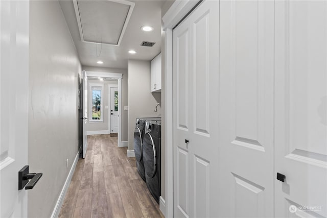 washroom with light hardwood / wood-style flooring, cabinets, and washing machine and clothes dryer