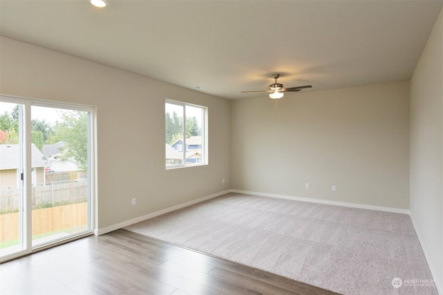 spare room featuring ceiling fan, a healthy amount of sunlight, and light hardwood / wood-style flooring