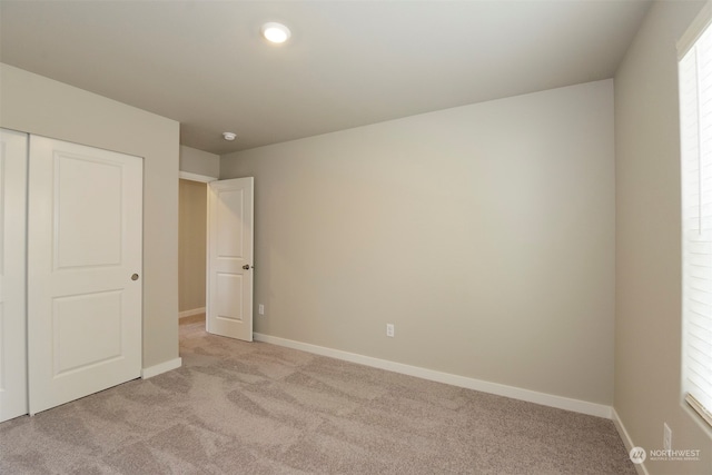 unfurnished bedroom with light carpet and a closet