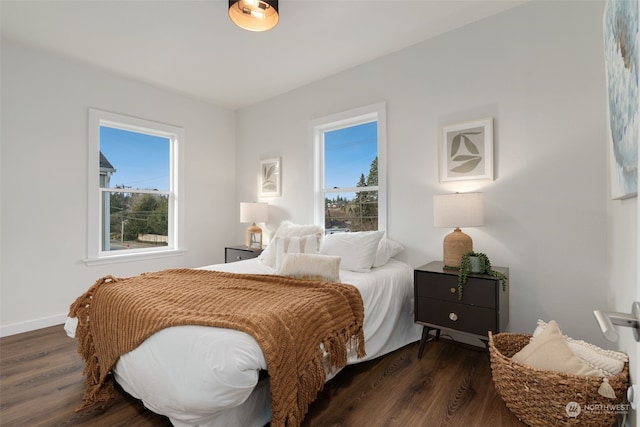 bedroom with multiple windows and dark hardwood / wood-style floors