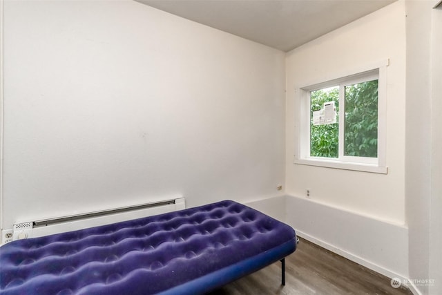 bedroom featuring baseboard heating and wood-type flooring
