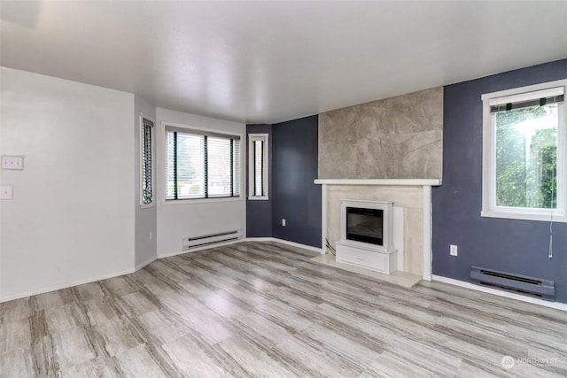 unfurnished living room with a baseboard radiator, light wood-type flooring, and a fireplace